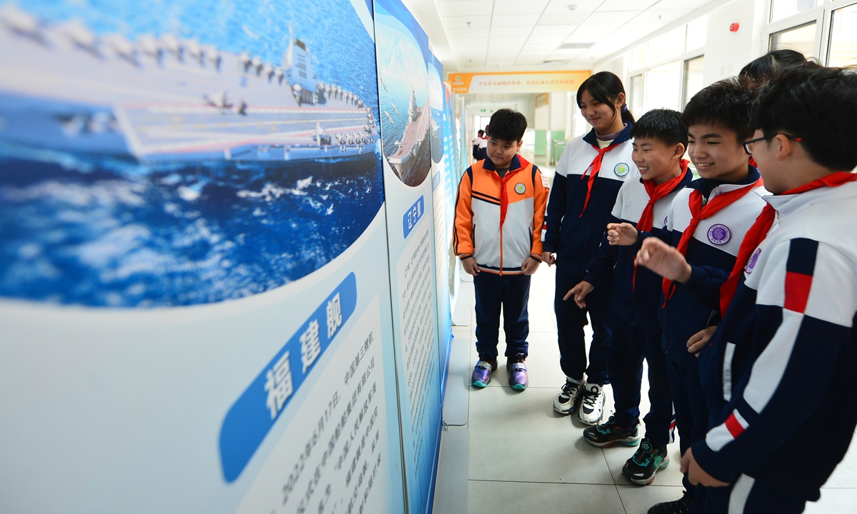 Students explore the aircraft carrier knowledge exhibition boards during a national defense education themed activity hosted by a primary school in Qingdao, East China's Shandong Province, on March 18, 2024. Photo: VCG