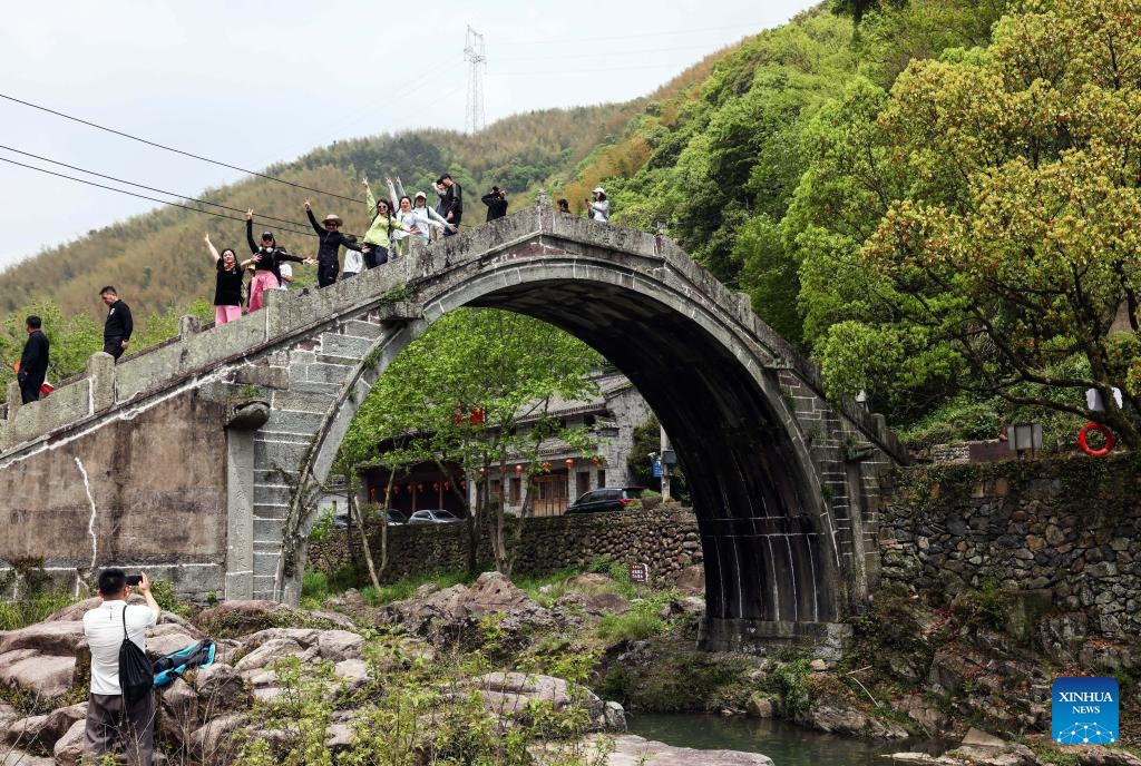 Tourists pose for photos on an ancient bridge at Zhongcun Village of Luting Township, Yuyao City, east China's Zhejiang Province, April 13, 2024. Sticking to the concept of lucid waters and lush mountains are invaluable assets, Luting Township has taken local environment as an advantage to develop ecological industry and to promote the countryside tourism.(Photo: Xinhua)