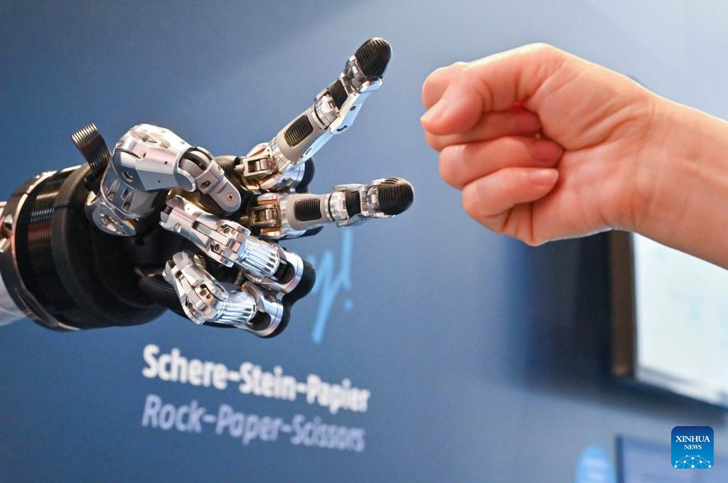 A visitor plays rock paper scissors with an intelligent robot at Hannover Messe in Hannover, Germany, on April 23, 2024. Hannover Messe 2024, Germany's leading industrial trade fair, kicked off on Monday with a clear emphasis on carbon-neutral production and hydrogen fuel cells.(Photo: Xinhua)