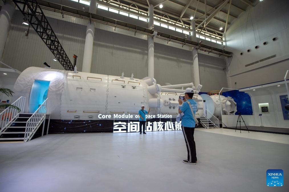 A visitor poses for a photo with a model of core module of space station at an exhibition on aerospace in Wuhan, central China's Hubei Province, April 23, 2024. The exhibition, as a part of the celebration of the Space Day of China this year, features science popularization and achievements of aerospace industry, exposing visitors to a comprehensive view of China's aerospace industry and its accomplishments in recent years.(Photo: Xinhua)