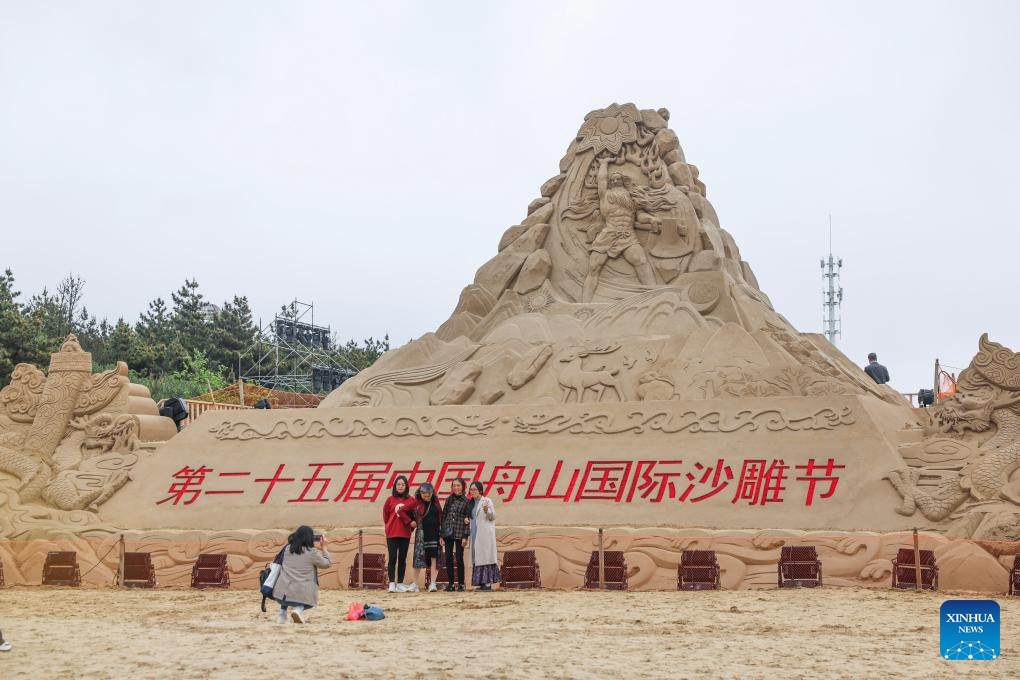 Tourists pose for photos in front of a sand sculpture at Nansha scenic area in Zhujiajian, Zhoushan City, east China's Zhejiang Province, April 22, 2024. The sand art creations are made for the 25th Zhoushan International Sand Sculpture Festival that coincides with the upcoming May Day holiday. The sculptures, inspired by Chinese dragon culture and the ancient literature Shan Hai Jing (Classic of Mountains and Seas), are promoted as a specialty to attract tourists.(Photo: Xinhua)