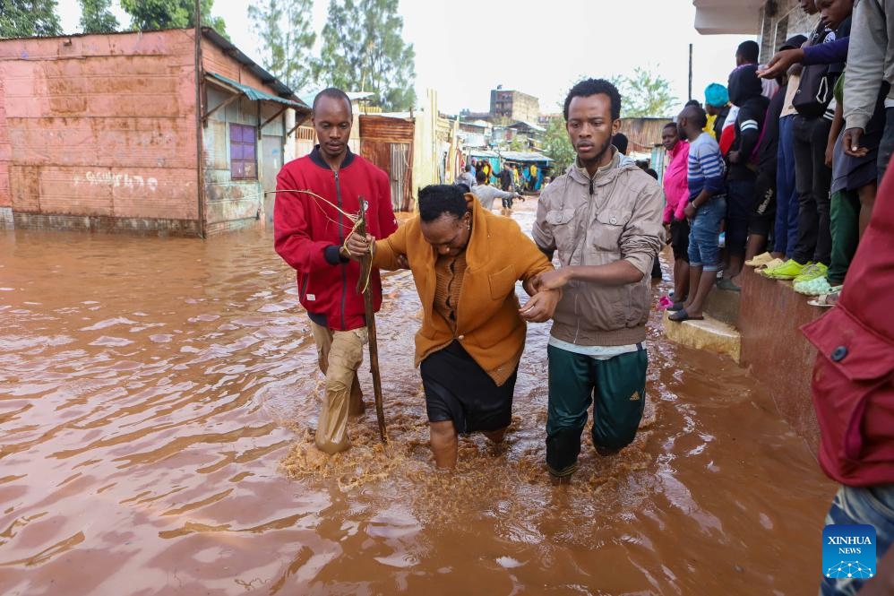 Residents assist a woman through floodwater after heavy rains in the Mathare slums of Nairobi, Kenya, on April 24, 2024. Kenya is experiencing heavy rains that have disrupted normal business across the East African country, resulting in the loss of more than 38 lives and the destruction of property.(Photo: Xinhua)