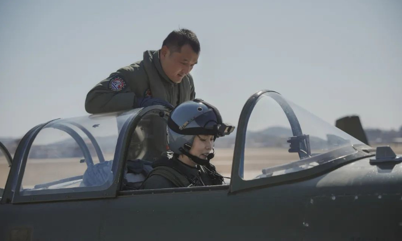 A member of the first group of female carrier-based aircraft pilots in China prepares for a maiden flight. A flight instructor guides the trainee pilot. Photo: Chen Chao 