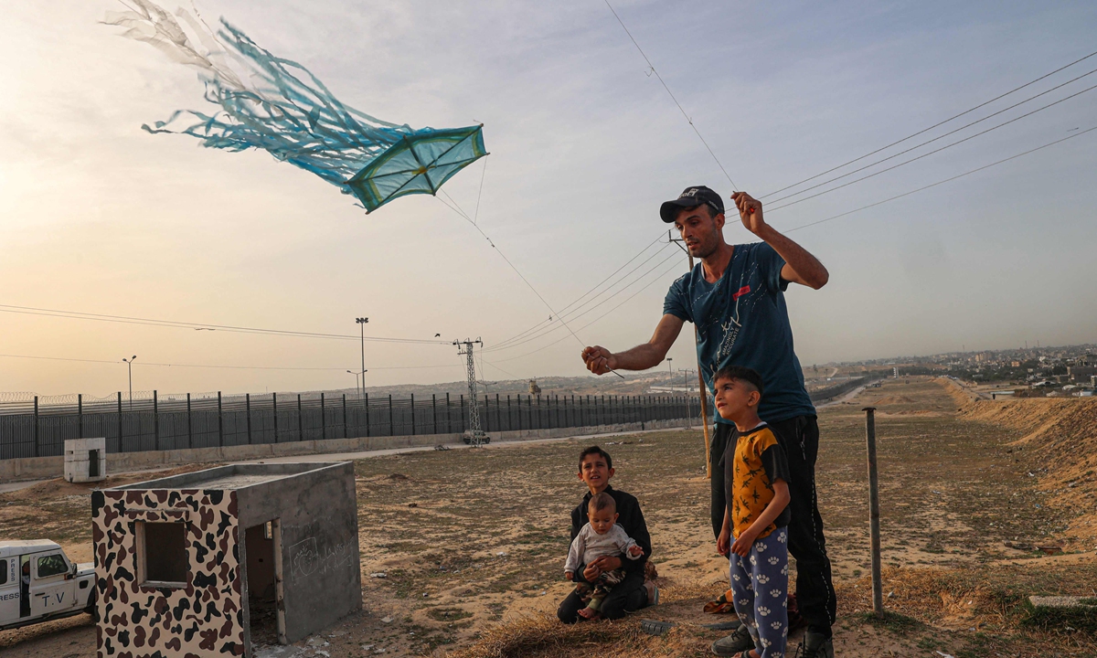A displaced Palestinian man helps a child to fly a kite near the border with Egypt in Rafah in the southern Gaza Strip on March 28, 2024. Photo: VCG