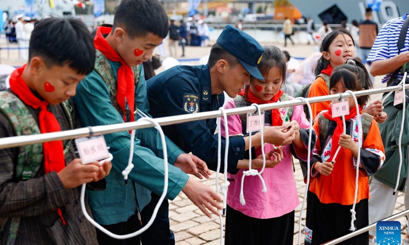 Children learn to tie knots under the instruction of a navy solider during an open day event of the Chinese People's Liberation Army (PLA) Navy in Qingdao, east China's Shandong Province, April 20, 2024. This year marks the 75th founding anniversary of the Chinese People's Liberation Army (PLA) Navy.(Photo: Xinhua)