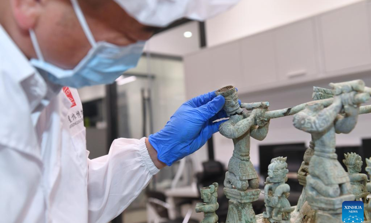 Guo Hanzhong compares two parts of a figure on a bronze altar at Sanxingdui Museum in Guanghan City, southwest China's Sichuan Province, May 30, 2023. Photo:Xinhua