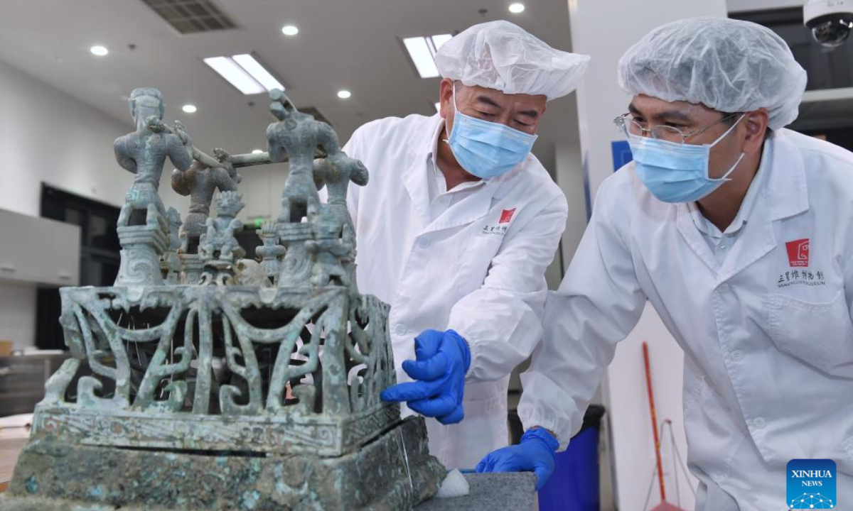 Guo Hanzhong (L) discusses the restoration plan of a bronze altar with his colleague at Sanxingdui Museum in Guanghan City, southwest China's Sichuan Province, May 30, 2023. Guo Hanzhong is the vice head of the cultural relics storage department of the Sanxingdui Museum in southwest China's Sichuan Province. The 56-year-old man is skilled in the craft of restoring cultural relics. In the past 40 years, he has restored more than 6,000 cultural relic items and was deeply involved in the excavation of all the eight 