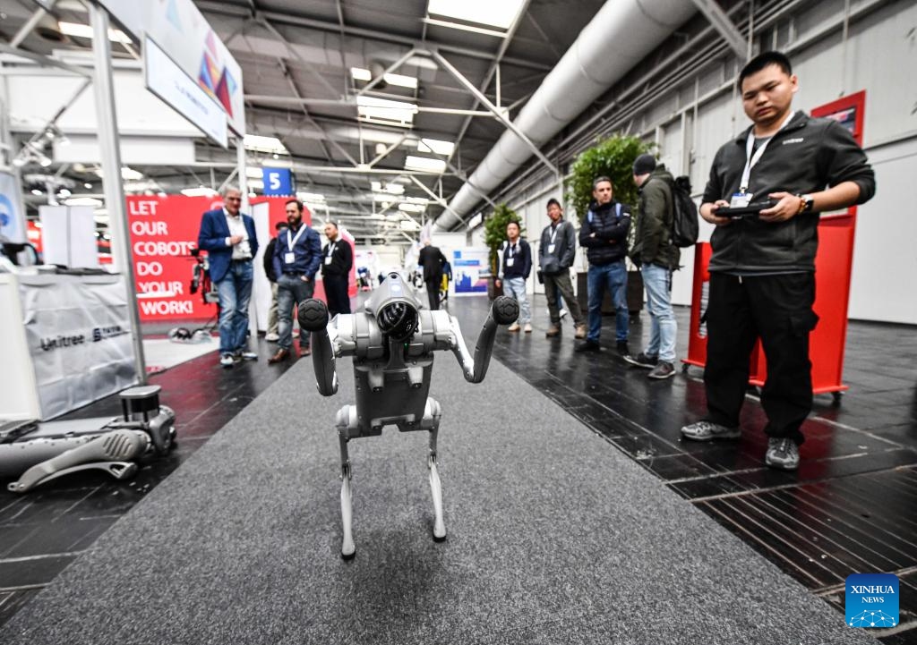A staff member of Hangzhou Yushu Technology Co., Ltd. (1st R) demonstrates a robotic dog at Hannover Messe 2024 in Hannover, Germany, April 22, 2024. The exhibition, focused on energizing a sustainable industry, runs until Friday and attracted almost 4,000 exhibitors from around 60 countries and regions. Among them, Chinese exhibitors accounted for 30 percent of participants, second only to the host Germany, according to the organizer.(Photo: Xinhua)