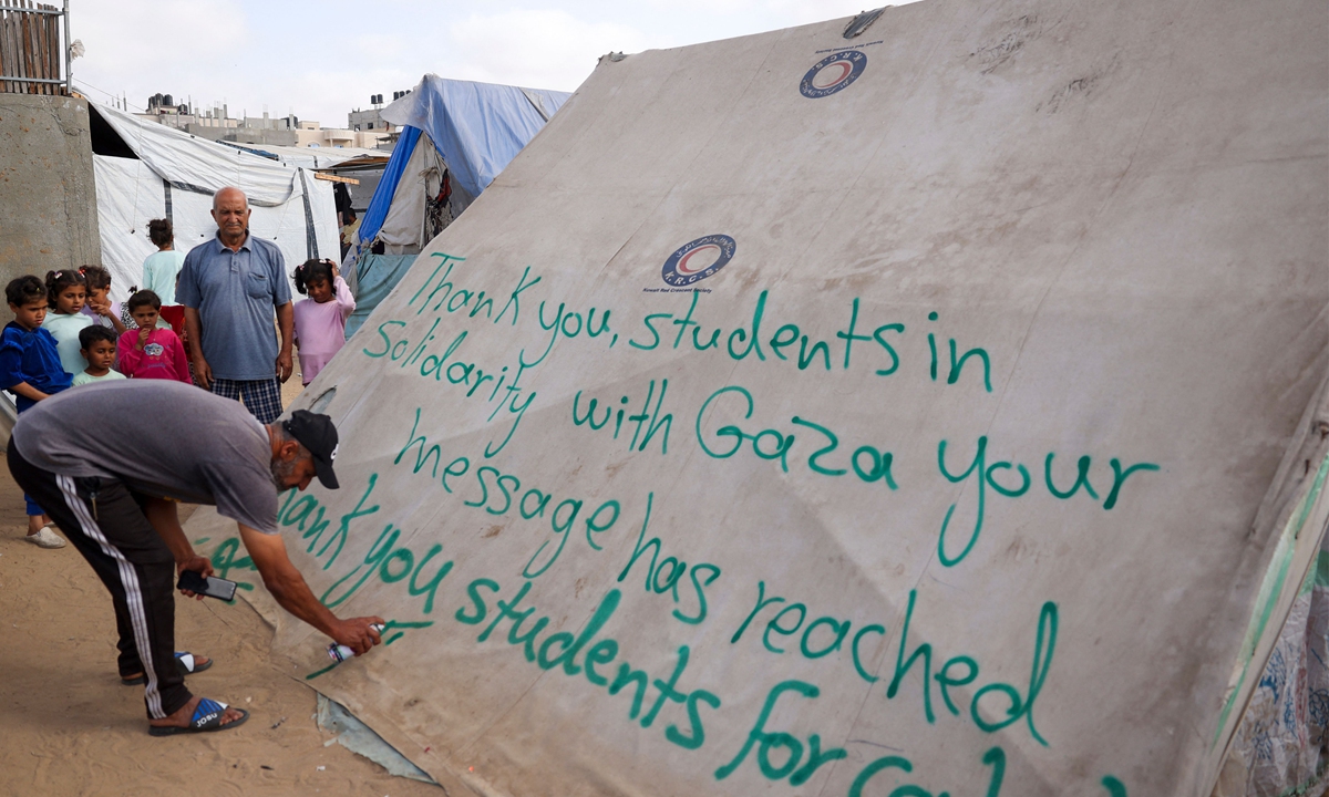 A man writes a message of thanks to students in the US protesting in solidarity with the people of Gaza, on a tent at a camp for displaced Palestinians in Rafah, in the southern Gaza Strip on April 27, 2024, amid the ongoing conflict. Photo: VCG