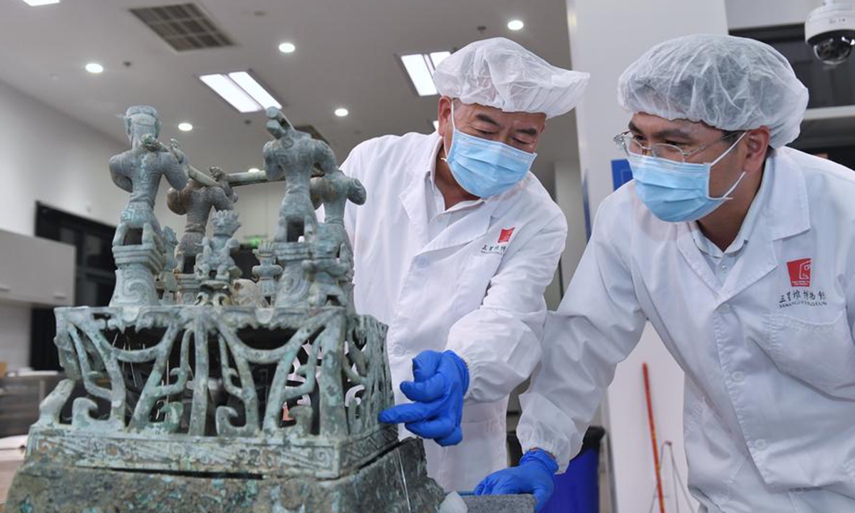 Guo Hanzhong (L) discusses the restoration plan of a bronze altar with his colleague at Sanxingdui Museum in Guanghan City, southwest China's Sichuan Province, May 30, 2023. (Xinhua/Liu Kun)

