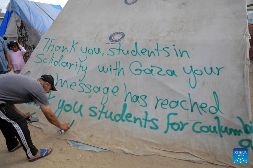 A man writes gratitude message on a tent in the southern Gaza Strip city of Rafah on April 27, 2024. Pro-Palestinian demonstrations are spreading on campuses across the United States as the Israel-Hamas conflict in Gaza continues. In the southern Gaza Strip city of Rafah, people write signs of gratitude towards those students on tents.(Photo: Xinhua)