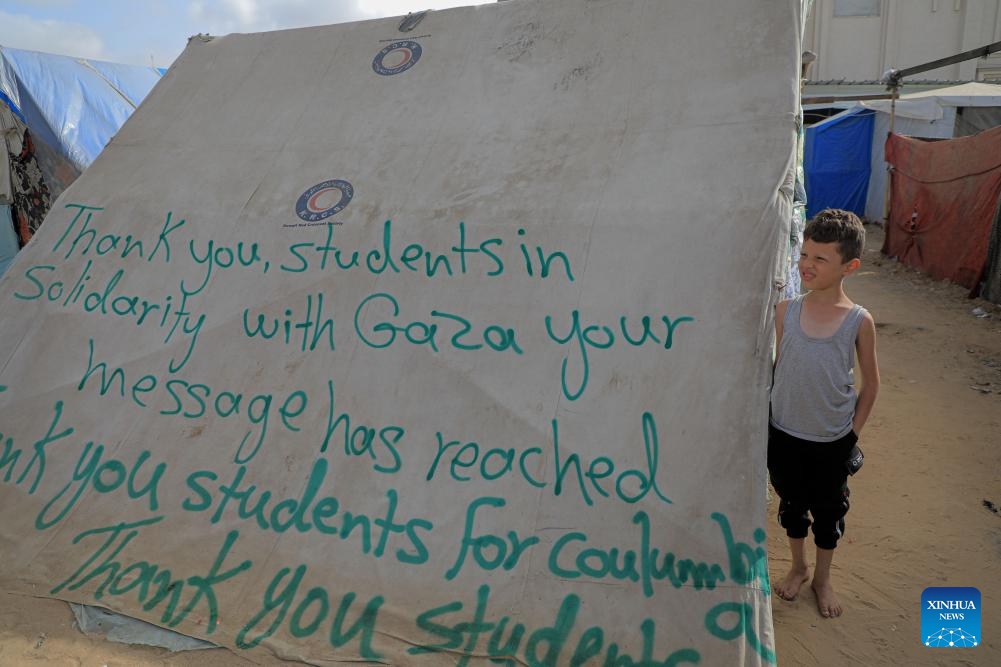 A boy stands next to a tent with signs of gratitude in the southern Gaza Strip city of Rafah on April 27, 2024. Pro-Palestinian demonstrations are spreading on campuses across the United States as the Israel-Hamas conflict in Gaza continues. In the southern Gaza Strip city of Rafah, people write signs of gratitude towards those students on tents.(Photo: Xinhua)