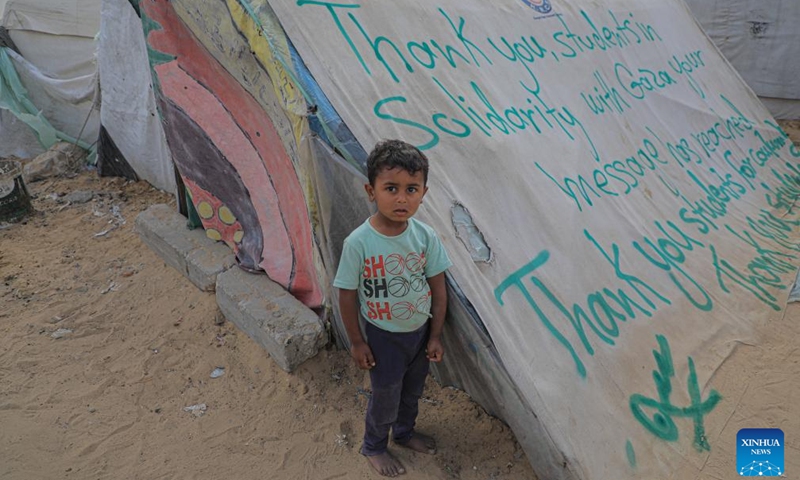 A boy stands next to a tent with signs of gratitude in the southern Gaza Strip city of Rafah on April 27, 2024. Pro-Palestinian demonstrations are spreading on campuses across the United States as the Israel-Hamas conflict in Gaza continues. In the southern Gaza Strip city of Rafah, people write signs of gratitude towards those students on tents.(Photo: Xinhua)