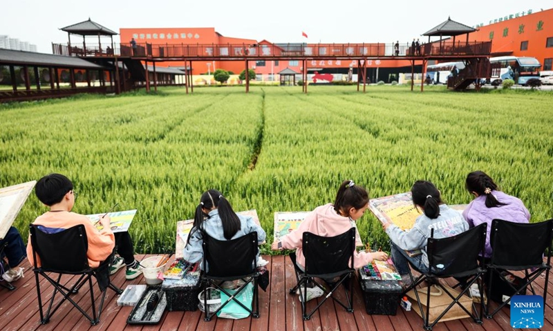 Children draw pictures beside the fields at Yuxin Town of Nanhu District in Jiaxing City, east China's Zhejiang Province, April 27, 2024. As a demonstration zone for harmonious and beautiful village, the Nanhu District has developed industries including study tour, village-level exhibition, and outdoor activity with joint efforts of local authorities, enterprises, collectives, and farmers to increase incomes and boost rural revitalization. (Xinhua/Lan Hongguang)