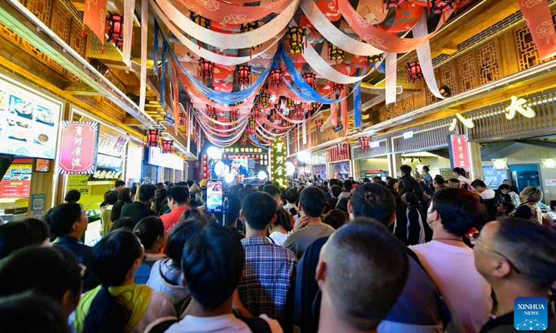 Tourists watch a performance at a gourmet street of Chengguan District in Lanzhou, capital of northwest China's Gansu Province, April 26, 2024. As the May Day holiday is approaching, Lanzhou has continued to promote the development of night economy, releasing new vitality for consumption. (Xinhua/Lang Bingbing)