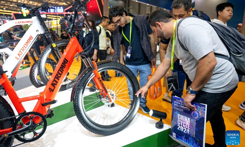 Brazilian exhibitors look at a bike displayed at the 32nd China International Bicycle Fair in east China's Shanghai, May 5, 2024. The event kicked off here on Sunday, drawing about 1,460 enterprises to participate. Photo: Xinhua