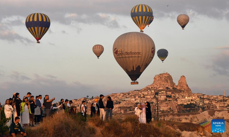 People watch hot air balloons flying over Cappadocia in Nevsehir, Türkiye on May 5, 2024. (Mustafa Kaya/Handout via Xinhua)