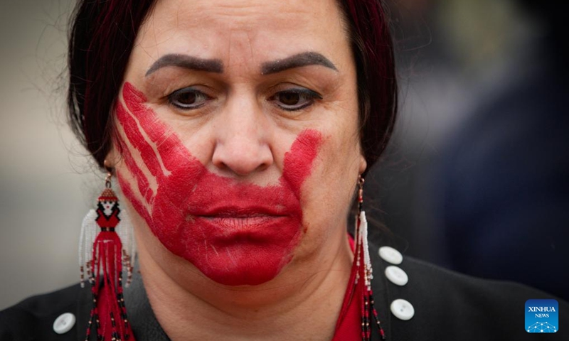An indigenous woman bearing hand-shaped paint mark over her mouth is seen during the Red Dress Day ceremony in New Westminster, British Columbia, Canada, on May 5, 2024. May 5 is the National Day of Awareness for Missing and Murdered Indigenous Women and Girls, also known as Red Dress Day, in Canada. Photo: Xinhua