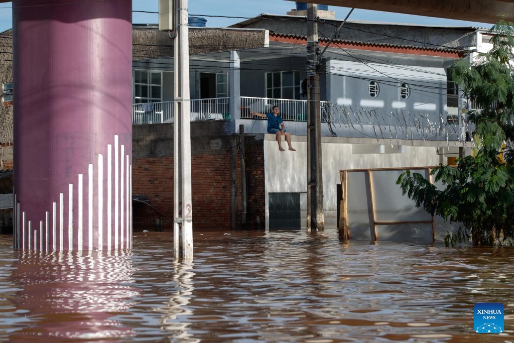 A man sits on the roof of the garage of a waterlogged house in Scharlau, Sao Leopoldo, in the state of Rio Grande do Sul, Brazil, May 7, 2024(Photo: Xinhua)