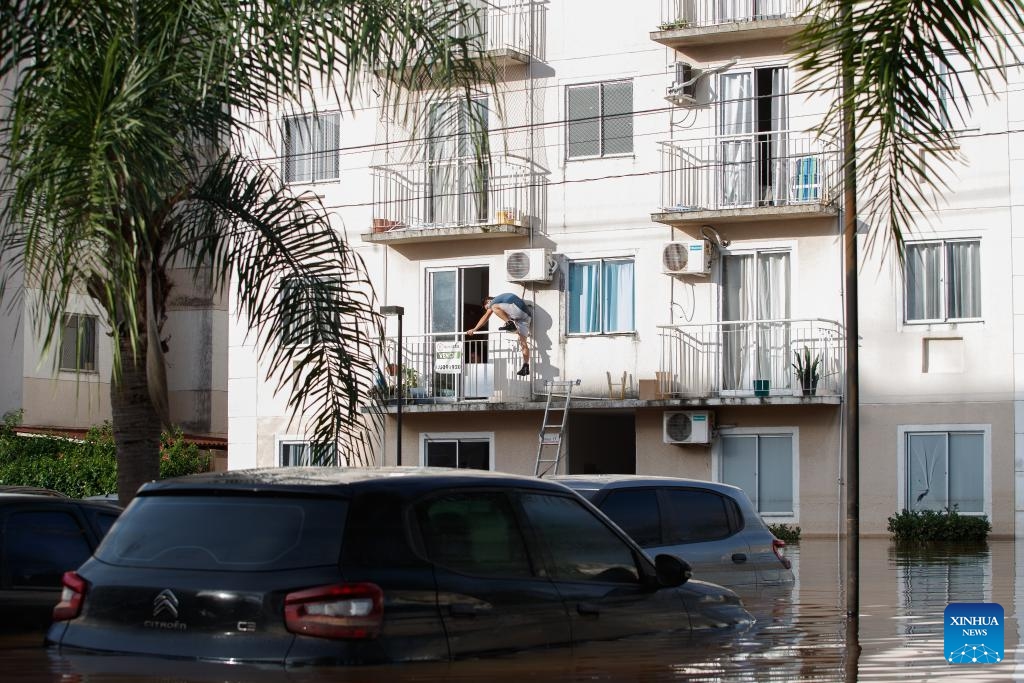 A man tries to get out the balcony of a building submerged by floods, in Scharlau, Sao Leopoldo, in the state of Rio Grande do Sul, Brazil, on May 7, 2024.(Photo: Xinhua)