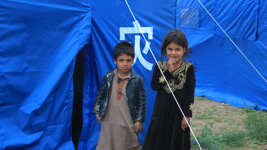 This photo taken on May 4, 2024 shows children in front of a China-donated tent for flood-affected residents in Adraskan District, west Afghanistan's Herat Province.(Photo: Xinhua)