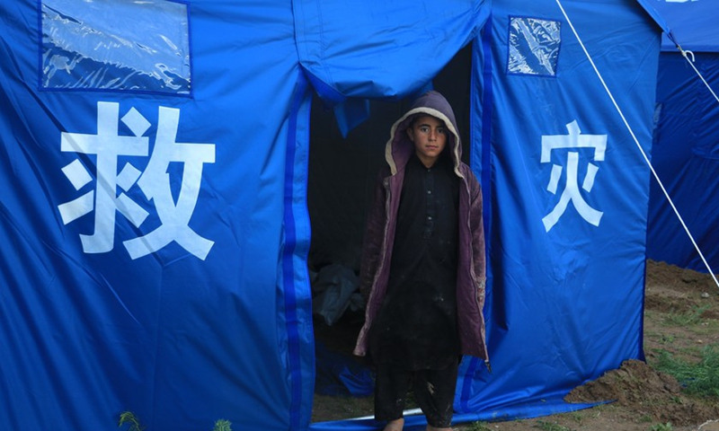 This photo taken on May 4, 2024 shows a boy in front of a China-donated tent for flood-affected residents in Adraskan District, west Afghanistan's Herat Province.(Photo: Xinhua)