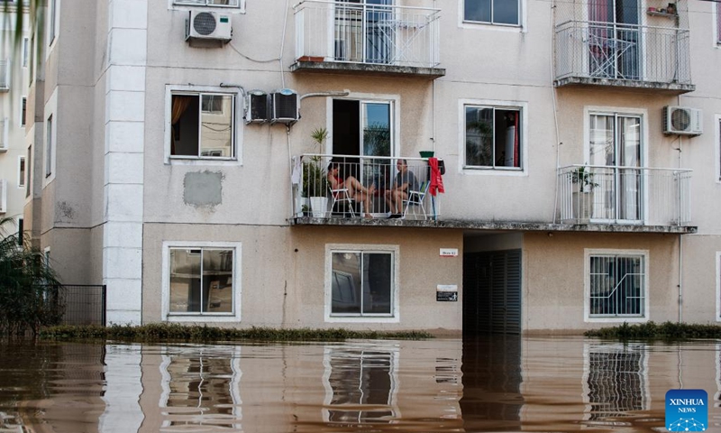 People are pictured at the balcony of a waterlogged building in Scharlau, Sao Leopoldo, in the state of Rio Grande do Sul, Brazil, on May 7, 2024.(Photo: Xinhua)