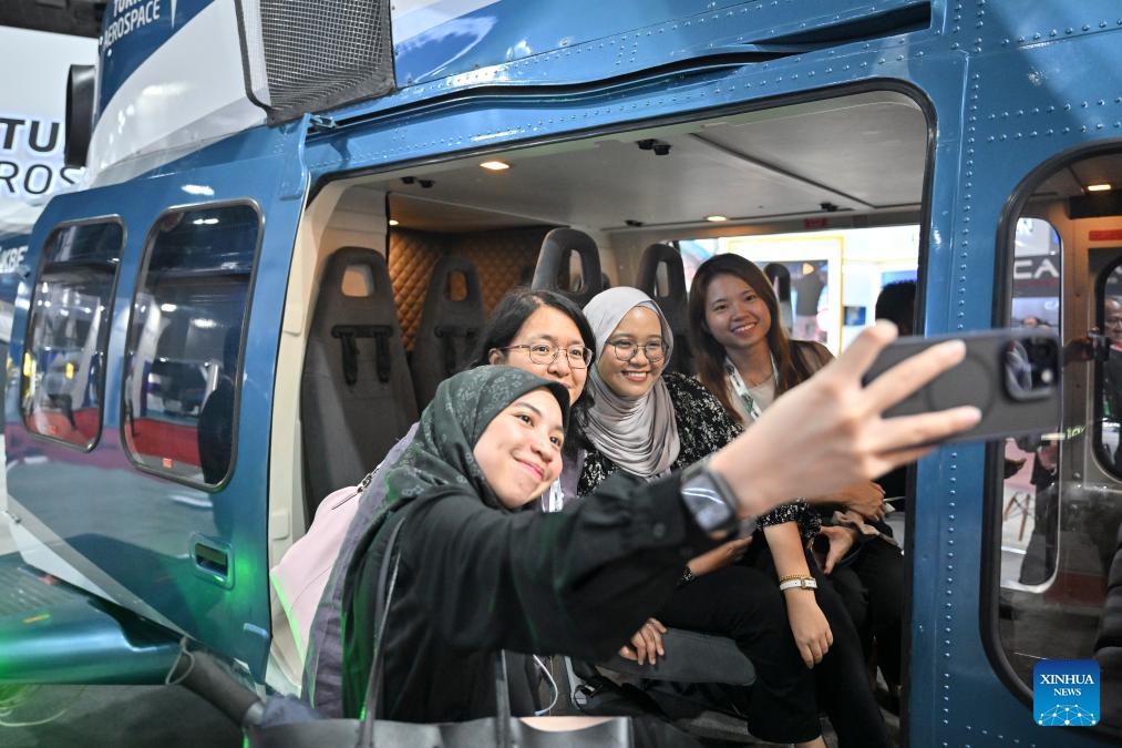 Visitor pose for a selfie with a helicopter displayed at Defense Services Asia 2024 in Kuala Lumpur, Malaysia, May 7, 2024. Defense Services Asia 2024, a biennial defense and weaponry show, opened in the Malaysian capital Kuala Lumpur on May 6.(Photo: Xinhua)
