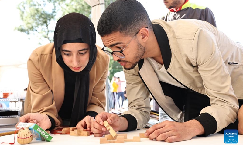 People try to solve Lu Ban Lock puzzle, a traditional Chinese toy, at the 20th world culture festival in Rabat, Morocco, May 8, 2024. The 20th world culture festival of the Rabat School of Mines kicked off here on Wednesday. Chinese paper-cutting, Lu Ban Lock and painting of opera facial mask were welcomed by Moroccan students.(Photo: Xinhua)