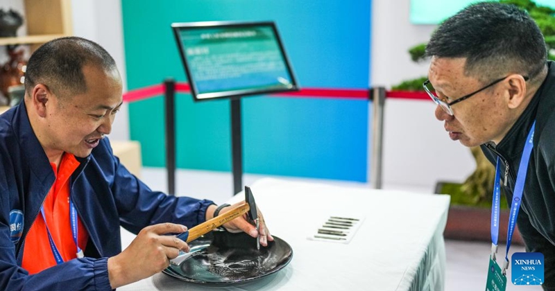 Chen Yinfu answers questions while making an artwork of Dafeng porcelain carving during a national vocational skills competition held in Guiyang, southwest China's Guizhou Province, May 8, 2024. Chen from Yancheng City of Jiangsu Province is an inheritor of Dafeng porcelain carving craftsmanship, which is a national-level intangible cultural heritage and allows artists to create dots and lines by cutting glaze with chisels on porcelain pieces. Photo: Xinhua