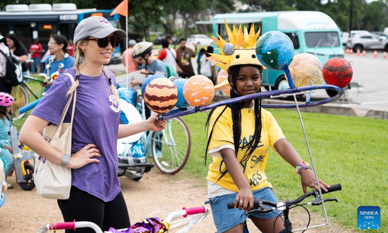 A girl (R) riding a solar system-themed art bike is seen at the 3rd Art Bike Parade & Festival in Houston, Texas, the United States, May 11, 2024. The annual event attracted hundreds of people to showcase their creativity in bike designing and enjoy various of activities. Photo: Xinhua