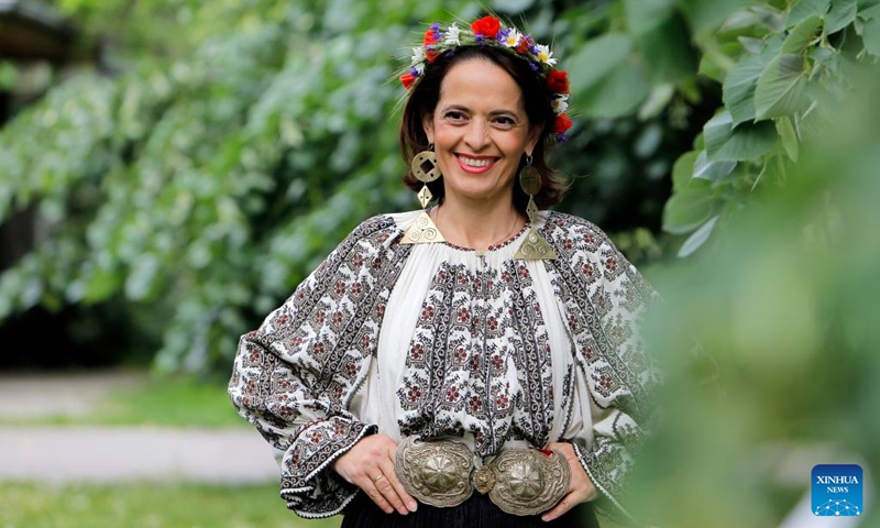 A woman wearing handmade traditional clothes poses during an event celebrating Romanian traditional costume in Bucharest, Romania, May 12, 2024. Photo: Xinhua