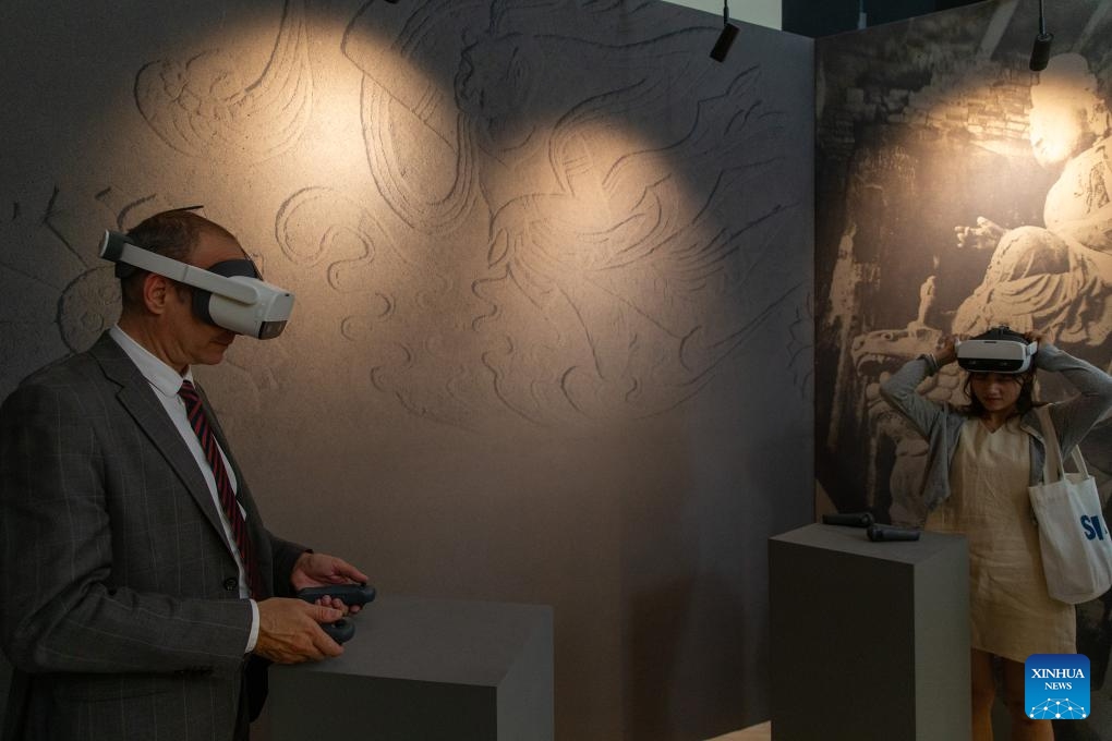 A visitor uses a VR device to view the art of Chinese grottoes at Zappeion Hall in Athens, Greece, May 11, 2024. The International Touring Exhibition of the Digital Restoration of the Tianlong Mountain Grottoes was held in Athens and attracted many visitors.(Photo: Xinhua)