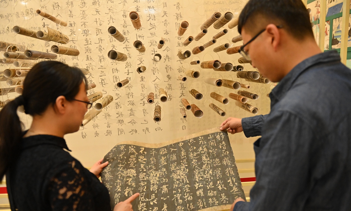 Zhao Xiaoxing (left) shows and introduces the replicas of documents unearthed from the Dunhuang Library Cave to a journalist at the Dunhuang Art Gallery in Lanzhou, Northwest China's Gansu Province. Photo: VCG