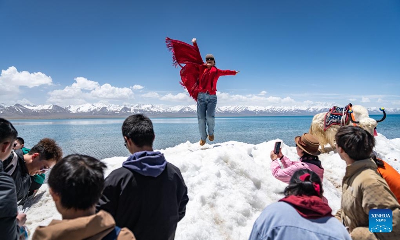 A tourist poses for photos by the Lake Namtso in southwest China's Xizang Autonomous Region, May 19, 2024. As temperature rises and ice melts, the Lake Namtso will enter its tourism season. Photo: Xinhua