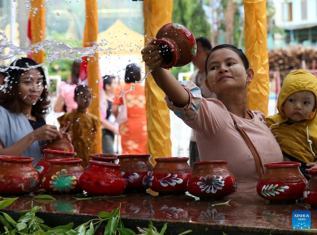 A woman waters a Bodhi tree on the Fullmoon Day of Kason at the Botahtaung Pagoda in Yangon, Myanmar, May 22, 2024.(Photo: Xinhua)