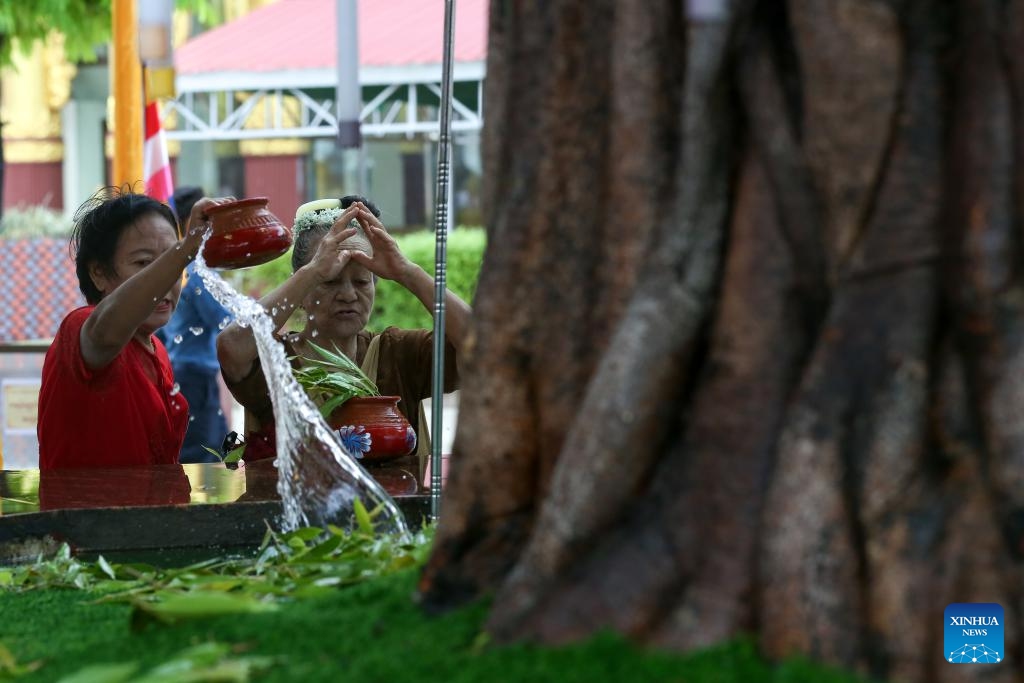 A woman waters a Bodhi tree on the Fullmoon Day of Kason at the Botahtaung Pagoda in Yangon, Myanmar, May 22, 2024.(Photo: Xinhua)