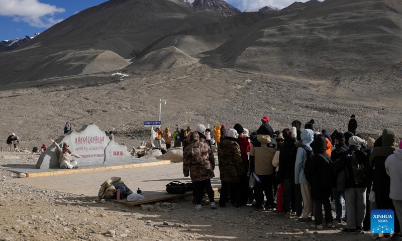 Tourists line up to take photos with the monument to the elevation survey of Mount Qomolangma in southwest China's Xizang Autonomous Region, May 24, 2024. The Mount Qomolangma National Park has entered peak tourism season. From Jan. 1 to May 20 this year, the Mount Qomolangma scenic spot has received about 136,000 tourists. (Photo:Xinhua)