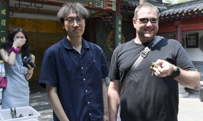 Visitors are invited to make zongzi and experience traditional Dragon Boat Festival customs in Jinan, East China's Shandong Province on June 6, 2024. The photo shows Damian, a tourist from Australia (right), displaying the zongzi he has made. Photo: VCG