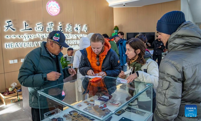 Natalia Yanina (2nd L), a tourist from Russia, and Simona Borghesio (2nd R), a tourist from Italy, stamp postcards in a post office at the Mount Qomolangma base camp for tourists in Zhaxizom Township of Tingri County in Xigaze City, southwest China's Xizang Autonomous Region, May 24, 2024. (Photo: Xinhua)
