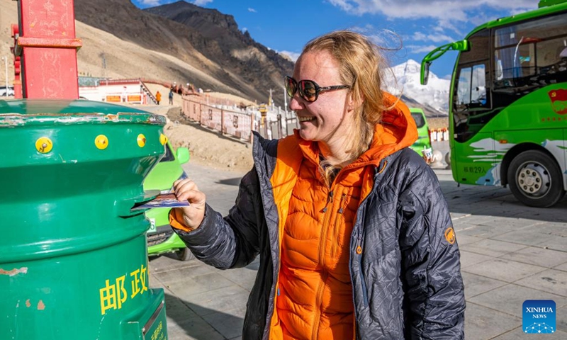 Natalia Yanina, a tourist from Russia, slips a postcard into a mailbox at the Mount Qomolangma base camp for tourists in Zhaxizom Township of Tingri County in Xigaze City, southwest China's Xizang Autonomous Region, May 24, 2024. The Mount Qomolangma National Park has entered peak tourism season. In 2023, the scenic spot had received about 464,000 tourists, and saw its ticket revenue totaling 110 million yuan (about 15.2 million U.S. dollars). (Photo: Xinhua)