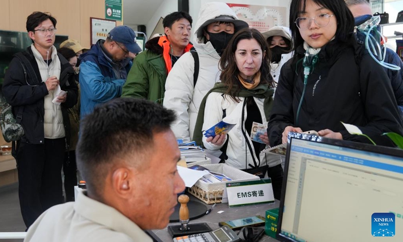 Simona Borghesio (2nd R), a tourist from Italy, lines up to buy postcards in a post office at the Mount Qomolangma base camp for tourists in Zhaxizom Township of Tingri County in Xigaze City, southwest China's Xizang Autonomous Region, May 24, 2024. (Photo: Xinhua)
