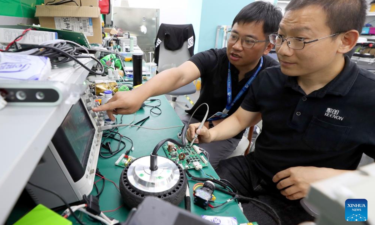 Tang Xuanlai (L) and his colleague debug a circuit board at Keenon Robotics in Shanghai, east China, May 30, 2024.(Photo: Xinhua)