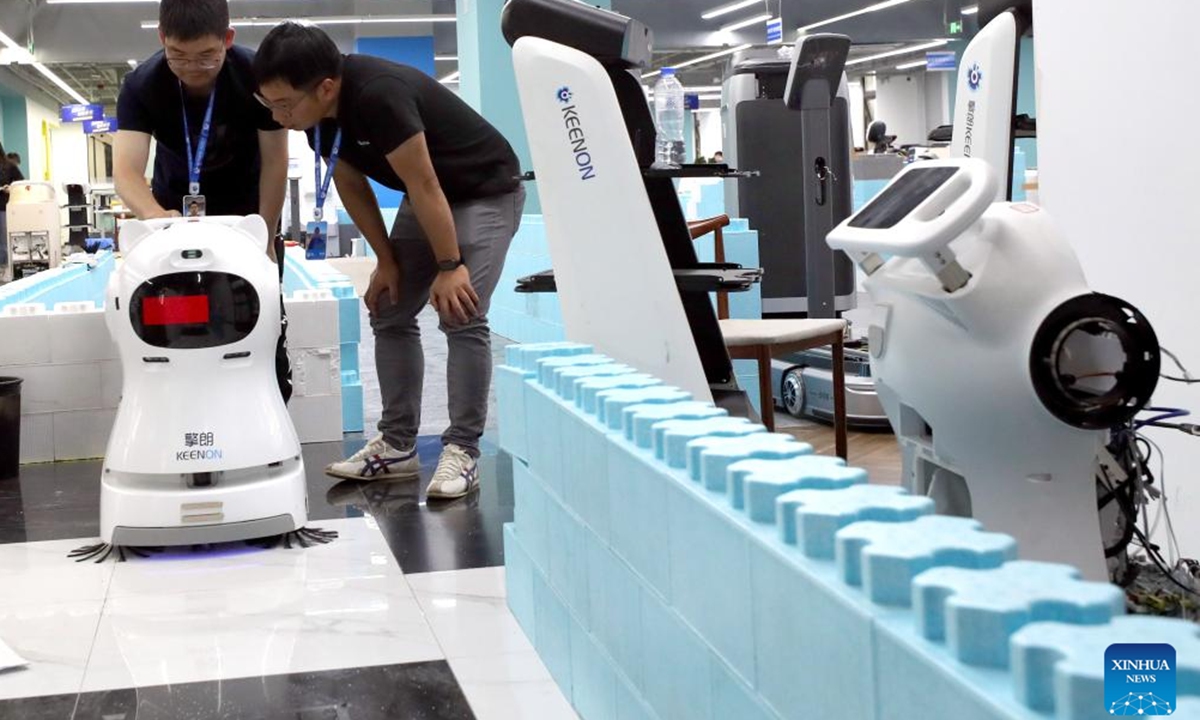 Tang Xuanlai (R) and his colleague work at a robot testing field of Keenon Robotics in Shanghai, east China, May 31, 2024. (Photo: Xinhua)