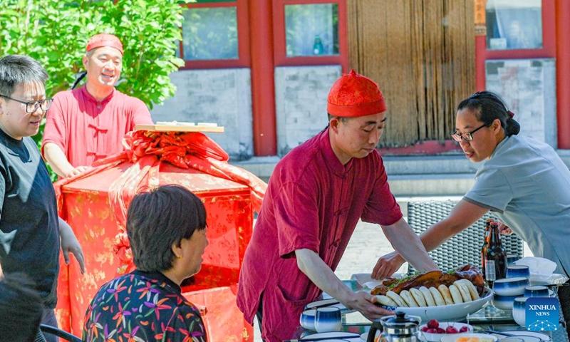 Waiters serve local delicacy to customers in Shixia Village in Yanqing District of Beijing, capital of China, June 1, 2024. Shixia Village in Yanqing District of Beijing was first built in the Ming Dynasty (1368-1644) and was once an important pass in the north of Juyongguan section of the Great Wall. (Photo: Xinhua)