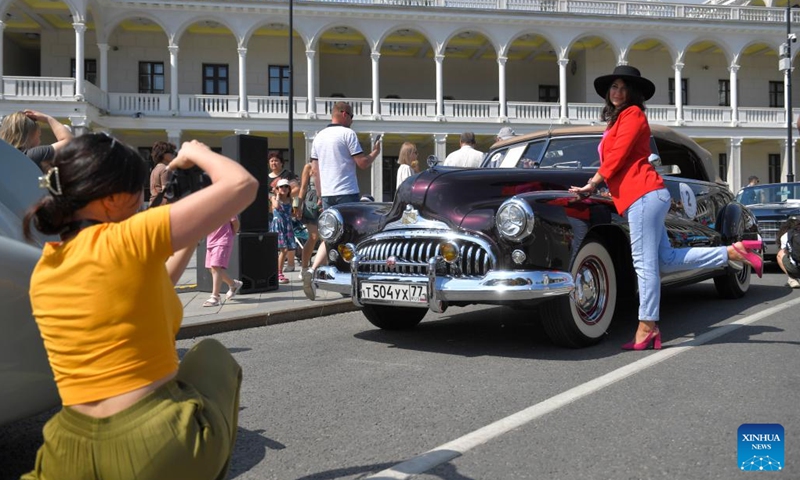 A woman poses for a photo with a retro car before the start of a retro car rally in Moscow, Russia, on June 2, 2024.(Photo: Xinhua)
