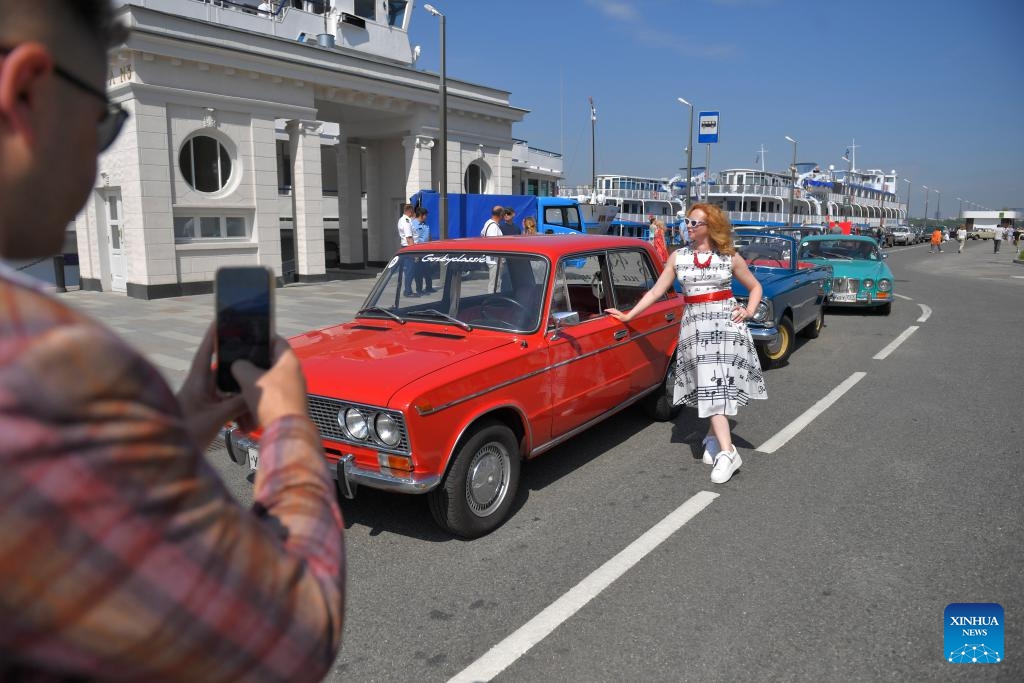 A woman poses for a photo with a retro car before the start of a retro car rally in Moscow, Russia, on June 2, 2024.(Photo: Xinhua)