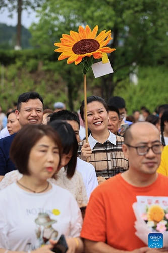 A parent holding a toy sunflower waits outside a national college entrance examination site in Suining City, southwest China's Sichuan Province, June 8, 2024. China's annual national college entrance examination, also known as Gaokao, started on Friday. The exam in some regions has ended on Saturday. (Photo by Liu Changsong/Xinhua)





