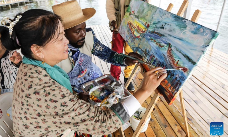 Ugandan and Chinese artists create an oil painting together during a dragon boat race held on the nearshore part of Lake Victoria in Entebbe, Uganda, June 9, 2024. The government of Uganda and the Chinese Embassy in the Eastern African country have jointly launched a tourism season between the two countries, with a dragon boat race held ahead of the traditional Chinese Dragon Boat Festival.(Photo: Xinhua)