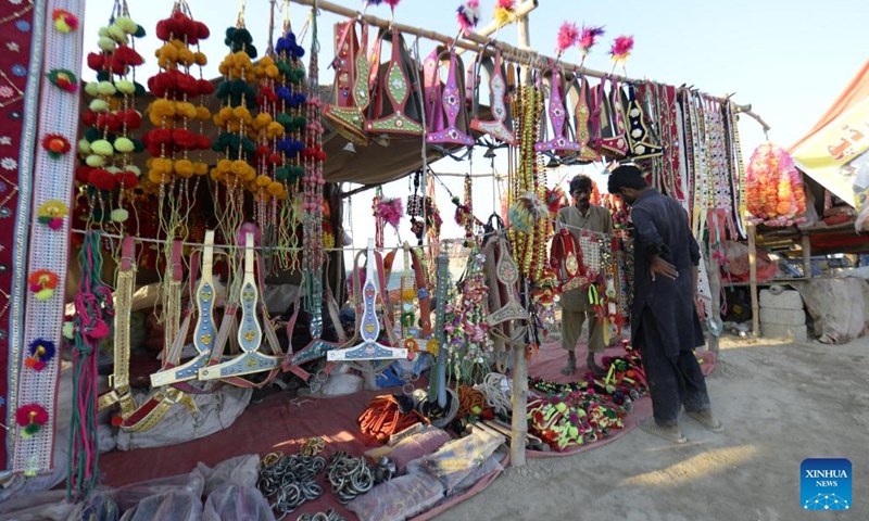 A man buys decoration items for animals at a livestock market ahead of Eid al-Adha festival in Islamabad, capital of Pakistan on June 11, 2024. (Photo: Xinhua)